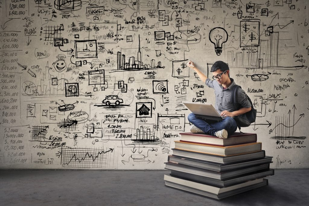 Student sitting on books developing ideas